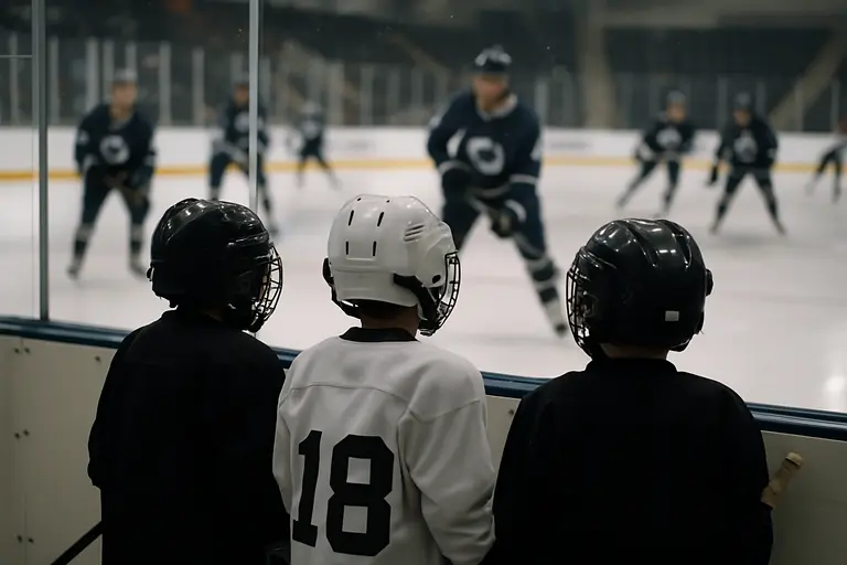 Young hockey players watching a professional team practice from rinkside